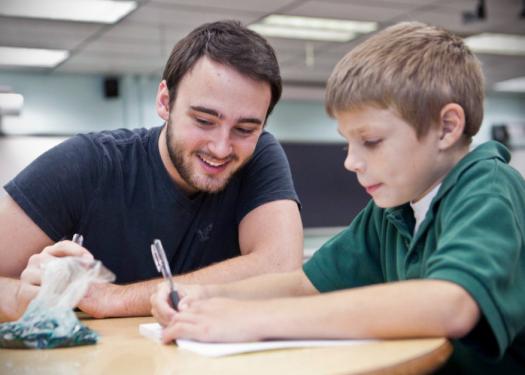STOCK PHOTO - Teacher smiling helping hard-working student