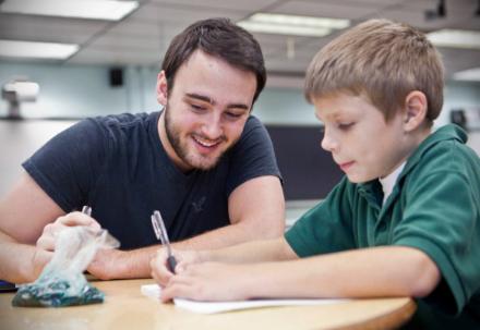 STOCK PHOTO - Teacher smiling helping hard-working student