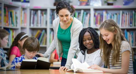 STOCK PHOTO - Teacher smiling working with students