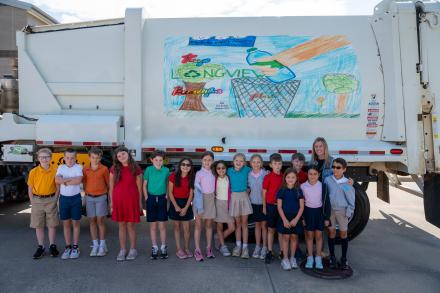 Hudson PEP students stand in front of a city truck that features art from one of the students